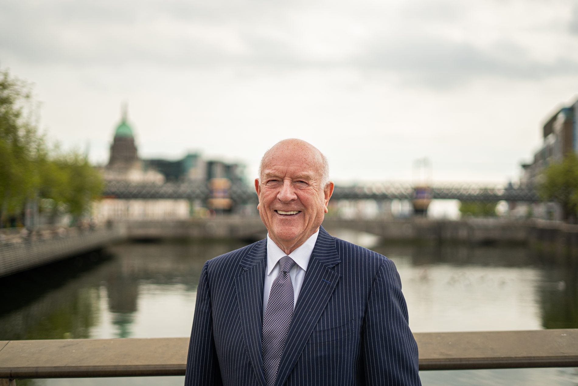 Portrait of a man in a navy pinstripe suit by the Liffey